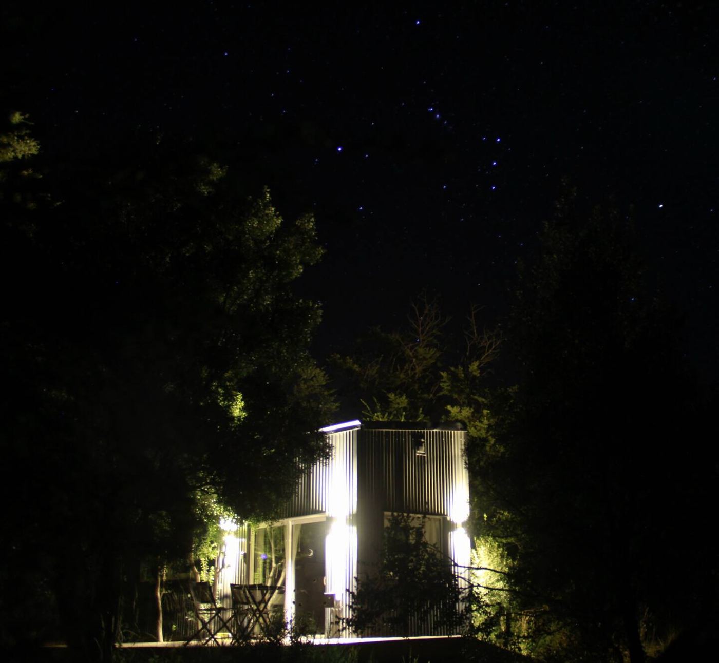 Tiny house iluminada de noche bajo las estrellas